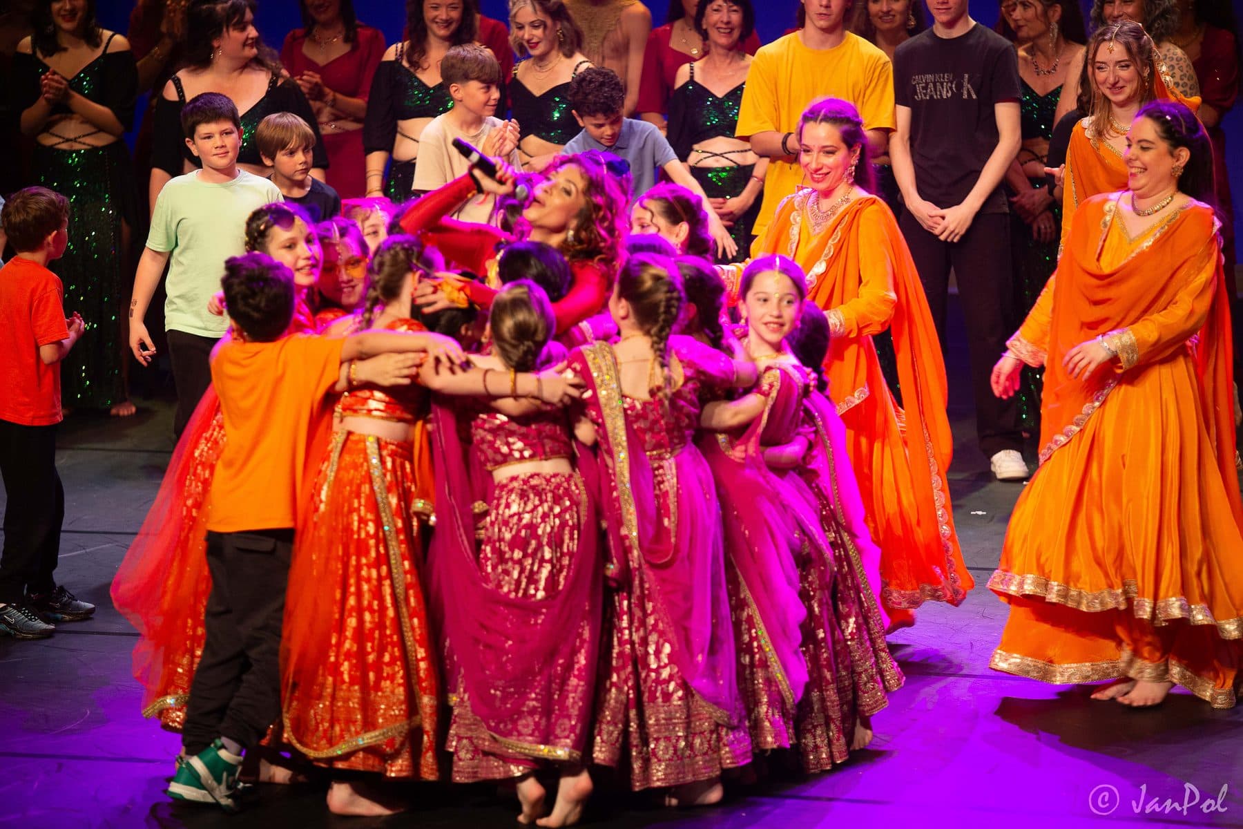 Groupe d'élèves en costumes orange et rose lors du salut final
